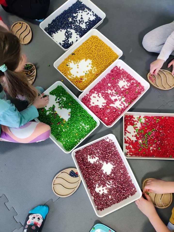 Dzieci wypełniają kartonowe jajka za pomocą pofarbowanych ziaren ciecierzycy