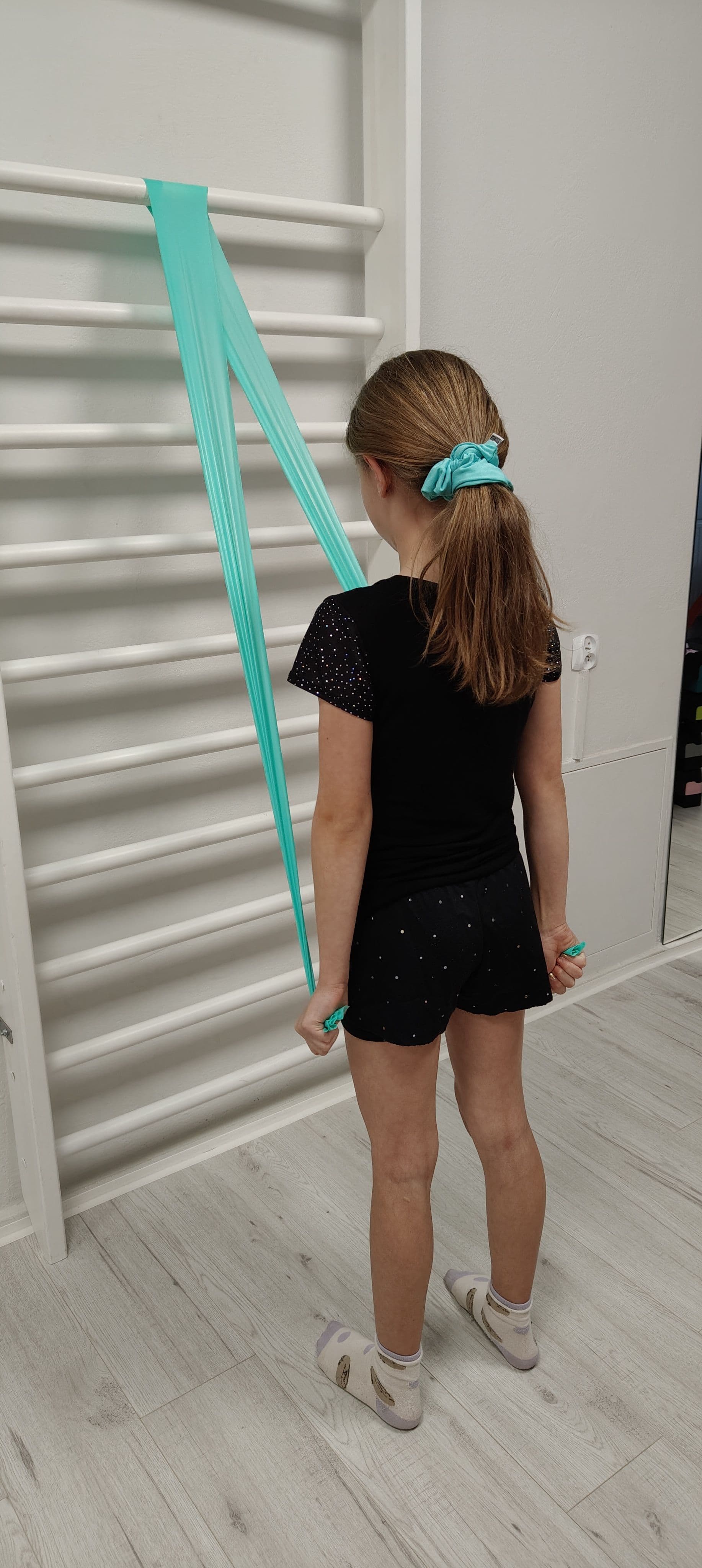 Dziewczynka ćwiczy z taśmą oporową przy drabinkach